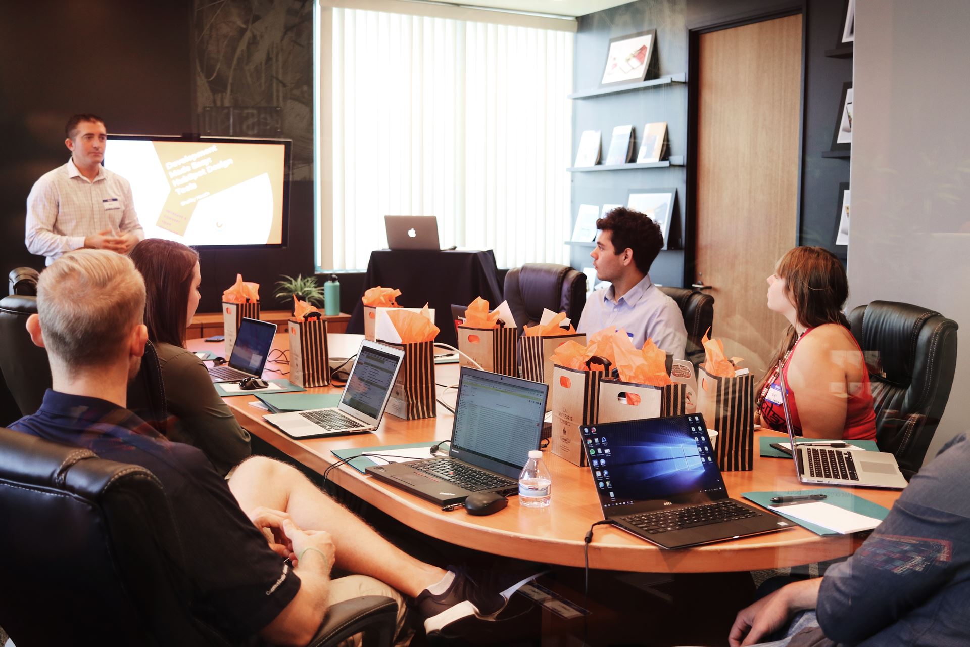 a group of people sitting at a table using a laptop computer